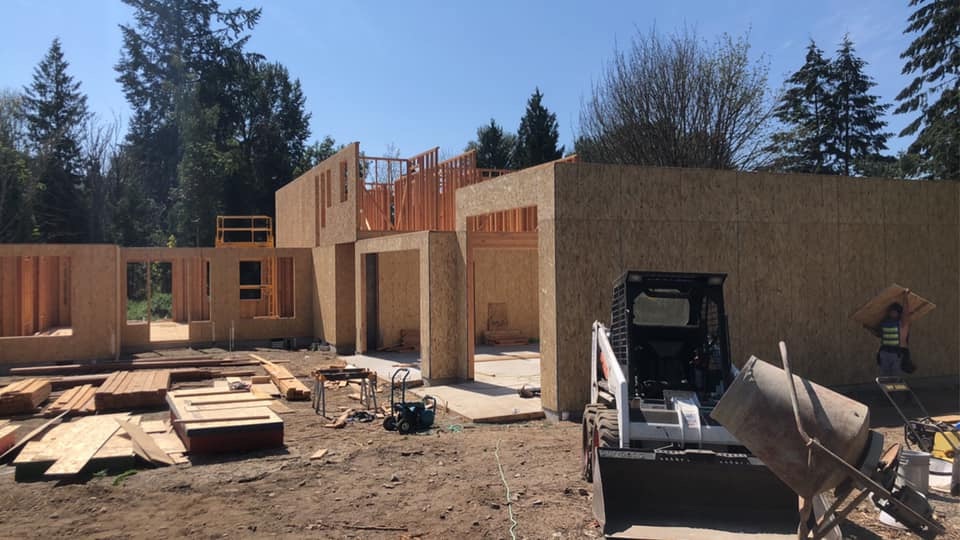 Active construction site with wall framing and heavy equipment during new home build